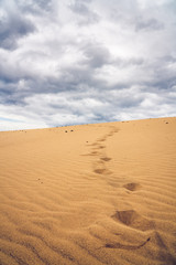 Fototapeta na wymiar Footprints on the sand dunes. Mystical skies in the background.