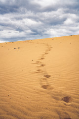 Footprints on the sand dunes. Mystical skies in the background.