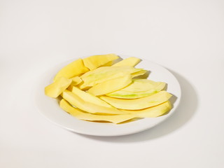 Medium ripe mango on white dish isolated on white background.