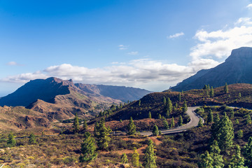Fototapeta na wymiar Beautifully lit dusty road horizon with monumental canyon mountains. Canary Islands.