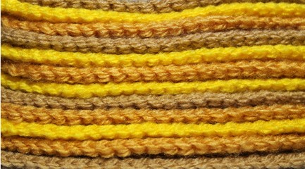 A pile of bright yellow and brown knitted elements. Warm and soft wallpaper, pattern, background