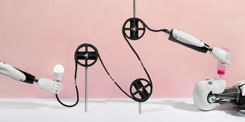 Creative robotic conveyor concept with plastic wheels and robot hands on pink background. Robot feeding from the baby bottle