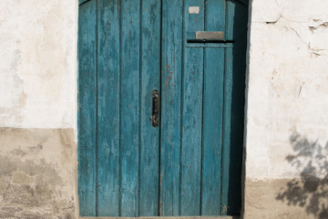 Old wooden door with handle, keyhole and post hole. Door with blue cracked paint. Wood texture.