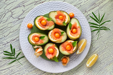 Avocado boats with smoked salmon, lemon, physalis and mint leaf, top view