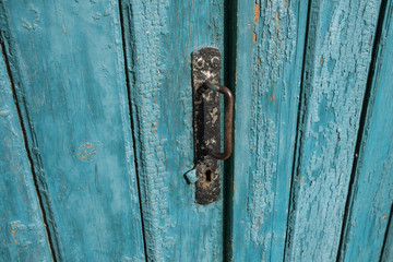 Old wooden door with handle, keyhole. Door with blue cracked paint. Wood texture.