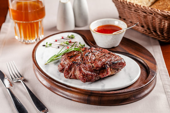 American cuisine concept. Pork steak with red tomato barbecue sauce. Serving dishes on a wooden board in a restaurant. Background image. copy space