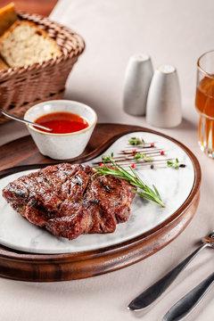 American cuisine concept. Pork steak with red tomato barbecue sauce. Serving dishes on a wooden board in a restaurant. Background image. copy space