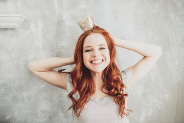 junge schöne Frau mit Krone lachend und roten Haaren 