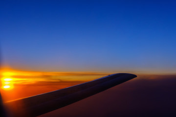 Fototapeta na wymiar View of the sunset and the wing of the aircraft from the porthole