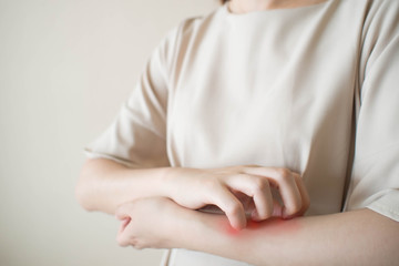 Young woman scratching arm from having itching. Cause of itchy skin include insect bites, eczema,...