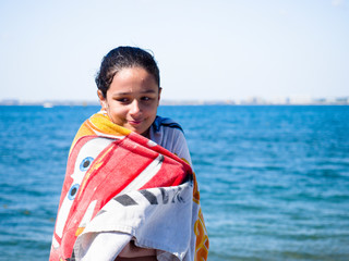 cute, dark-haired girl covered with towel at summer beach