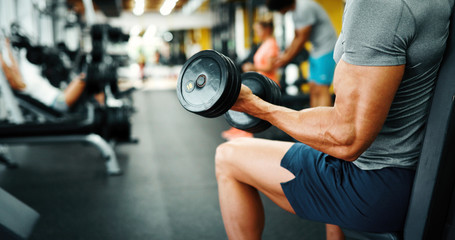 Fototapeta na wymiar Muscular bodybuilder guy doing exercises in gym