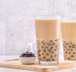 Obraz na płótnie Canvas Popular Taiwan drink - Bubble milk tea with tapioca pearl ball in drinking glass on marble white table wooden tray background, close up, copy space