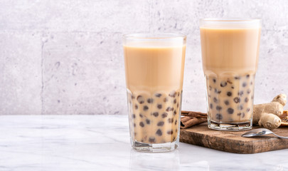 Popular Taiwan drink - Bubble milk tea with tapioca pearl ball in drinking glass on marble white table wooden tray background, close up, copy space