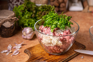 Minced meat with chopped onion and parsley in a glass plate.