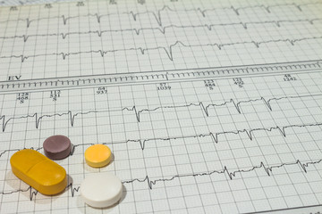 Some pills on electrocardiograms. Records of cardiac activity. Licensed drugs in forms of tablets. Concept of cardiovascular disease.