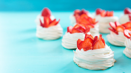 Beautiful pavlova cakes with strawberries on a blue background. Selective focus. Tasty sweet breackfast. Wedding morning. Meringue with cream.