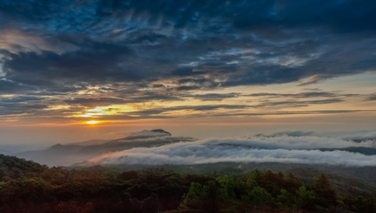 Fototapeta premium sunrise at Doi Inthanon, Km. 41 view point, mountain view misty morning on top hill panorama 180 degrees with sea of mist in valley and yellow sun light in the sky background, Chiang Mai, Thailand.