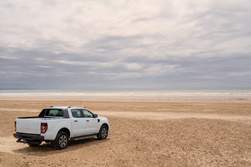 Fototapeta na wymiar Car on the beach with a view of the sea