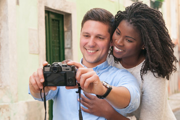 Happy intercultural couple taking selfie on photographic camera. Smiling beautiful young lovers...