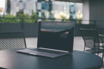 Open laptop on the table in street cafe outdoors, mock up, business, freelance concept