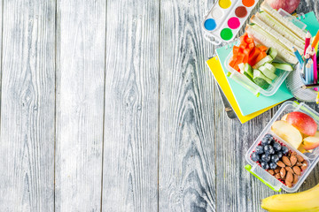 Healthy school lunch box. Kid's lunch box with sandwiches, fruit, vegetables, nuts, water and...