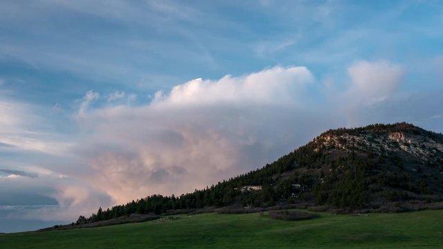 View of Bald Mountain as storm clouds move behind it at sunset in Larkspur Colorado.