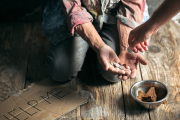 Fototapeta na wymiar Male beggar hands seeking money with sign HELP ME from human kindness on the wooden floor at public path way or street walkway. Homeless poor in the city. Problems with finance, place of residence.