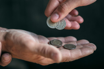 Male beggar hands seeking money, coins from human kindness on the wooden floor at public path way or street walkway. Homeless poor in the city. Problems with finance, place of residence.