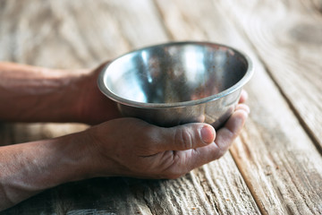Male beggar hands seeking money, coins from human kindness on the wooden floor at public path way...