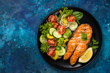 Grilled salmon fish steak with vegetables top view.