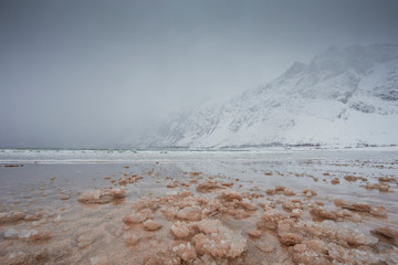 Beautiful seashore with high mountains and snowy sea in the Lofoten Islands in Norway