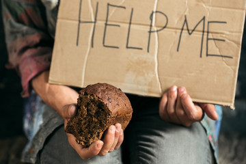 Male beggar hands seeking money with sign HELP ME from human kindness on the wooden floor at public...