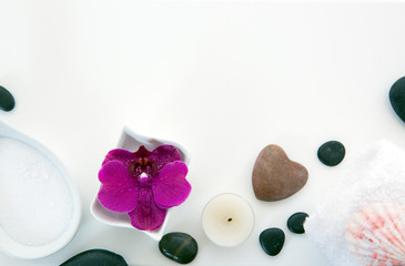 Spa setting with pink orchids, black stones and bath salts on wood background.