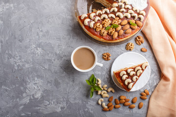 Homemade cake with caramel cream and nuts with cup of coffee on a gray concrete  background, top view.
