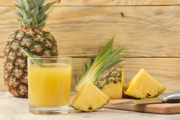 Fototapeta na wymiar Pineapple juice in a glass and pieces of fresh pineapple on a natural wooden background. summer. fruits.