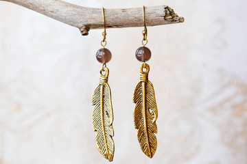 Mineral stone shade quartz and pearl beads feather shape earrings on neutral background © marbenzu