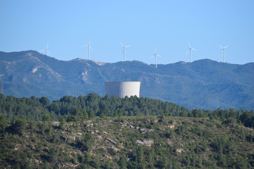 Paisaje campestre con vistas a una central nuclear y a unos molinos de viento.