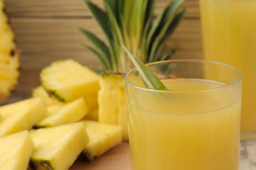 Pineapple juice in a glass and pieces of fresh pineapple on a natural wooden background. summer. fruits.