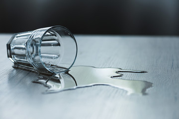 glass with spilled water on textured wooden surface