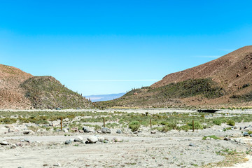 Blurred background of Atacama Desert landscape with snow-capped Andean volcanos, salt flat and some vegetation on horizon, Chile