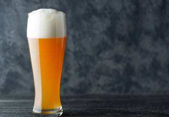 A glass of wheat unfiltered beer on a dark background with copyspace