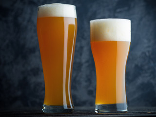 Two glasses of unfiltered cold wheat craft beer on a dark table