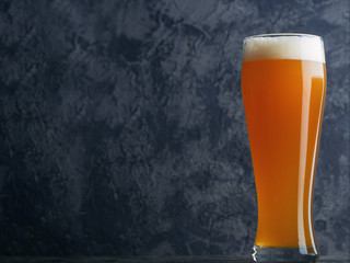 A glass of wheat unfiltered beer on a dark background with copyspace