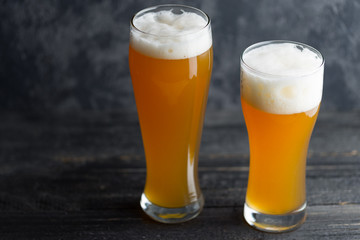 Two glasses of unfiltered cold wheat craft beer on a dark table
