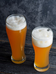 Two glasses of unfiltered cold wheat craft beer on a dark table