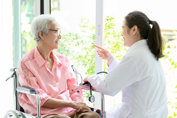 Happy senior asian woman and doctor or nurse talking,enjoying together,female caregiver or friendship supporting smiling elderly people in wheelchair,support,healthcare,family concept