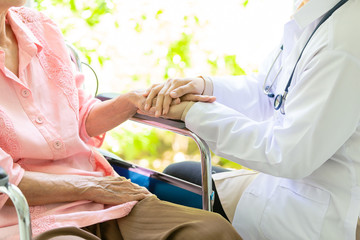 Closeup of hand medical female doctor or nurse holding senior patient hands and comforting her,.Caring caregiver woman supporting disabled elderly people on wheelchair,help,love,health care concept - obrazy, fototapety, plakaty