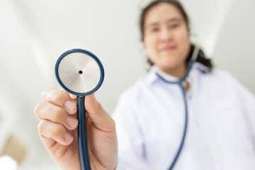 Asian female medical doctor holding stethoscope, young nurse checking patient using stethoscope,standing while looking at camera in hospital,health care concept