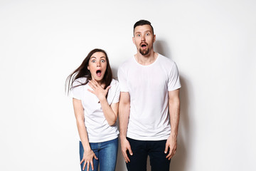 Shocked young couple on light background